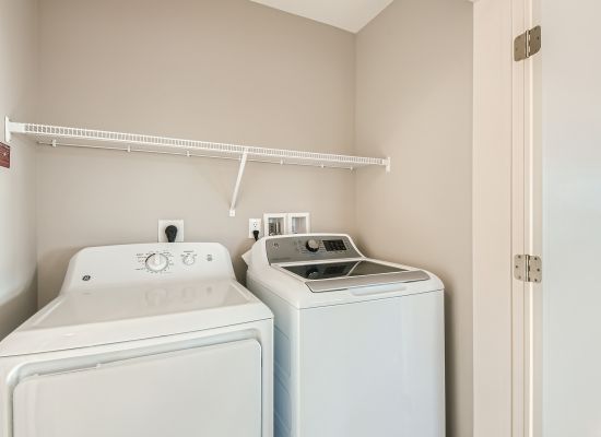 person doing laundry using in-home washer and dryer in apartment