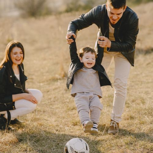 family playing soccer outside with child