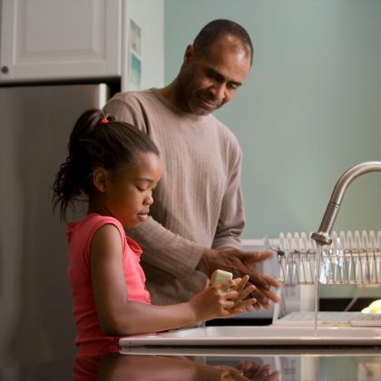 father and daughter doing dishes in their kitchen